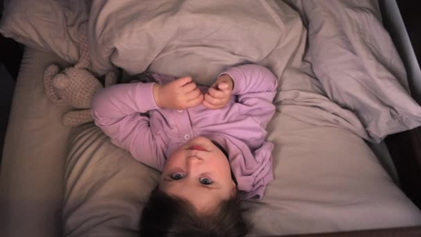 俯瞰在温暖的毛毯下 抱着玩具熊躺在舒适的枕头上 睡个好觉的学龄前小女孩面带微笑 快乐宁静的小女孩在床上享受着周末懒洋洋的早晨 — 图库视频影像