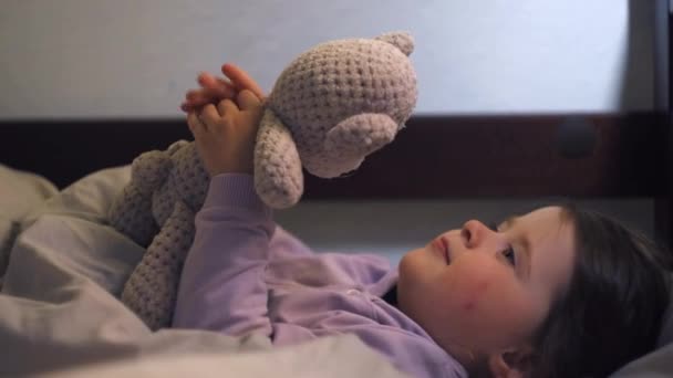 小女儿躺在温暖的毛毯下 抱着玩具熊躺在柔软的枕头上 睡个好觉 快乐宁静的小女孩在床上享受着周末懒洋洋的早晨 — 图库视频影像