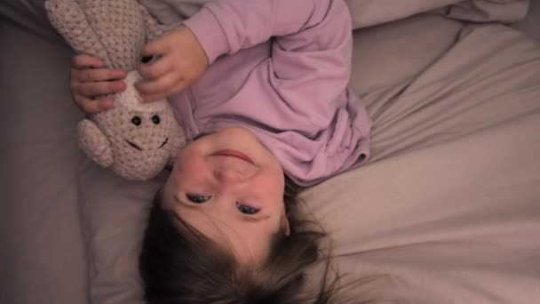 看到快乐的学龄前幼儿女儿躺在舒适的枕头下 毛毯下 玩具熊 有一个美好的夜晚休息 安静的小女孩在舒适的床上享受着周末懒洋洋的早晨 — 图库视频影像