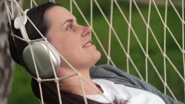 Klidná Žena Ležící Houpací Síti Poslouchající Hudbu Bezdrátovými Sluchátky Vychutnávající — Stock video
