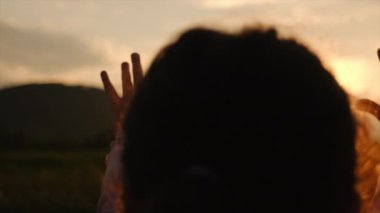 Mutlu rüya gören küçük kız silueti el ele tutuşuyor. Din yardım eli uzatır. Çocuk destansı günbatımında ya da gün doğumunda güzel yaz doğasının tadını çıkarıyor. Din kavramında dua etmek. Yavaş çekim