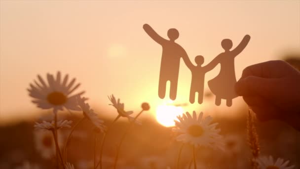 背景に小さな紙の家族の切り抜きを保持している子供の手の閉じる美しい暖かい日没 家族の家 里親ケア 世界精神保健デー 自閉症サポート 生活の概念の予算化コスト — ストック動画