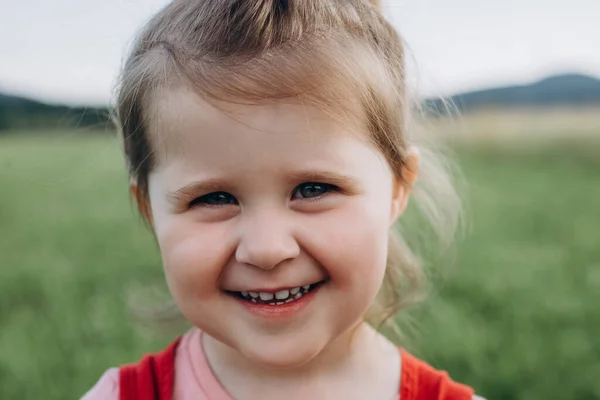 stock image Close up portrait of adorable smiling little girl kid, enjoying summer, warmth, freedom, happy looking at camera. Pretty small child with having fun outdoors. Childhood and summer concept