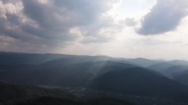 Destansı ve büyüleyici hava aracı görüntüleri. Kamera bulutlu bir günde güzel yaz dağlarının üzerinde uçuyor. Vahşi doğada büyük bir orman. Açık hava seyahati konsepti