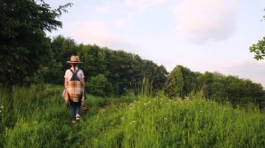 Şapkalı gezgin kız kamp ateşinin yanında tek başına mutlu tatiller geçiriyor. Çocuk doğa ormanlarında ateş yakıyor. Mutluluk özgürlük sorumluluk tatili seyahati