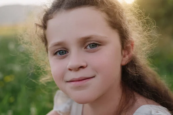 stock image Pretty happy kid poses funny and smiling enjoying outdoors during sunset. Close up portrait of charming little girl looking at camera with laughing and giggling expression. Childhood and leisure time