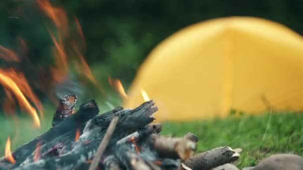 黄昏时分 在黄色帐篷和森林的背景下 靠近美丽的篝火 游客篝火与火花在晚上的时候在空气中飞行 探索户外生活方式的营地位置 — 图库视频影像