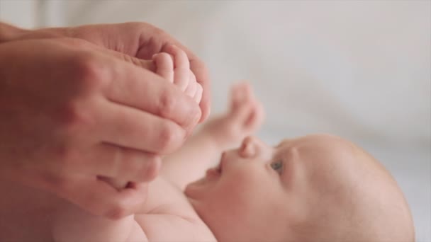 按摩师按摩小宝宝的手 按摩师按摩小宝宝的手指 快乐的男婴在家里躺在舒适的白色床上做婴儿按摩护理父亲 5个月大的新生儿 — 图库视频影像
