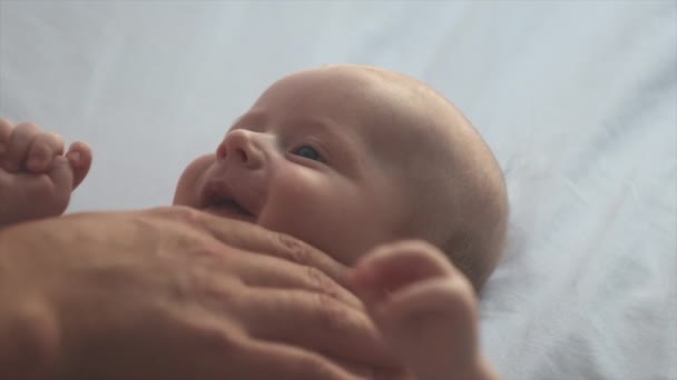 无法辨认的父亲按摩小宝宝的侧视图 新生儿皮肤护理的概念 预防结肠炎 男性手按摩新生儿 慢动作可爱的婴儿躺在舒适的床上 — 图库视频影像