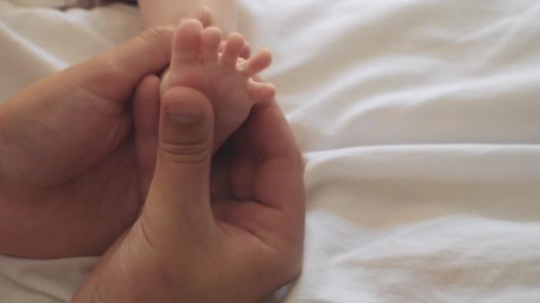 Zbliżenie Kochający Młody Tata Masuje Stopy Dziecka Leżąc Przytulnym Łóżku — Wideo stockowe