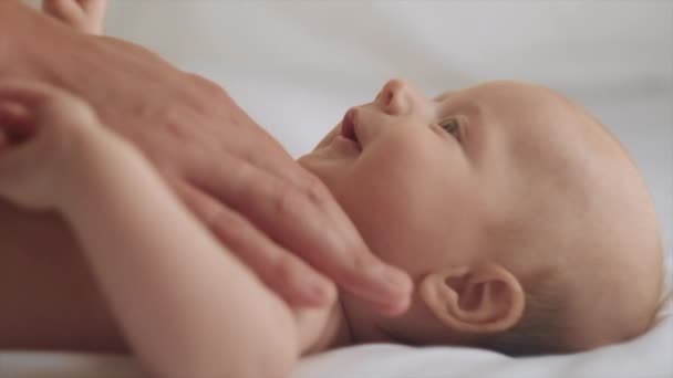 小爸爸给小宝宝按摩的特写镜头 新生儿皮肤护理的概念 预防结肠炎 男性手按摩新生儿 慢动作漂亮的高加索婴儿躺在舒适的床上 — 图库视频影像