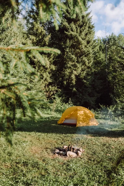 夏の朝に美しい緑の森の近くに設定されたキャンプファイヤーとキャンプテントのインスピレーション画像 ワンダーツーアドベンチャーコンセプト ハイキングライフスタイル スカンジナビアの自然を探索する — ストック写真