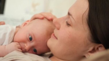 Bakımlı genç bir anne kucağında bebek, evde rahat bir yatakta uzanmış, gözleri kapalı tatlı bir çocuk, çocuk bakımı, annelik, ebeveynlik, şefkatli bir çocuk, şefkat konsepti.