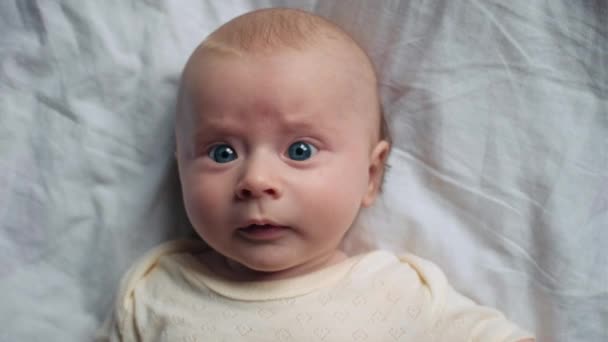 家の居心地の良いベッドに横たわる美しい甘い新生児のクローズアップトップビュー 笑って カメラを見ている幸せ かわいい赤ん坊の肖像画 ベビーシッター ヘルスケア 保育コンセプト — ストック動画