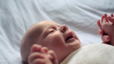 Seçici odak noktası, sevgi dolu genç bir anne, evde rahat bir yatakta uzanan sevimli küçük bir bebekle öpüşüyor. Kafkasyalı bir anne ve güzel bir çocuk olan oğlu yatak odasında eğleniyor.