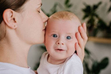 Sevgi dolu beyaz bir annenin sevimli, mutlu bir çocuğu öptüğünün yakın portresi. Oğlunun yanağı, ailenin şefkatli anı, güzel annenin evde kucak kucağa bekleyen oğluyla ilgilenmesi.