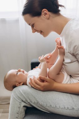 Neşeli, sevgi dolu genç bir anne kucağında yeni doğmuş bebeğiyle evde rahat bir kanepede otururken. Mutlu anne iyi istirahatler. Küçük tatlı bir çocukla anneliğin tadını çıkar. Ebeveynlik kavramı