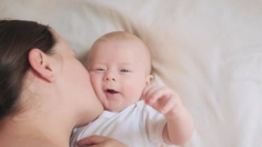 Yukarıyı kapayın mutlu, sevgi dolu bir anne, sevimli, gülümseyen bir bebek, sıcak, şefkatli bir yanak öpücükle tatlı bir bebekle konuşuyor. Şefkatli bir anne şımarık bir bebeği okşuyor. Annelik