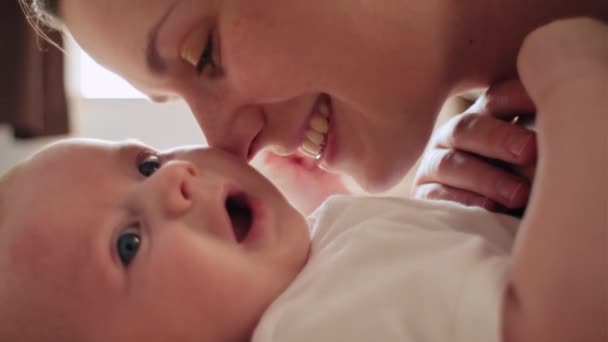 笑顔の笑顔の若い母親のカドルは 小さな生まれたばかりの赤ん坊の子供と一緒に一緒に遊びます 幸せな白人ママはベッドの上に横たわっている幼児の息子と母性を楽しみます 親のコンセプト — ストック動画