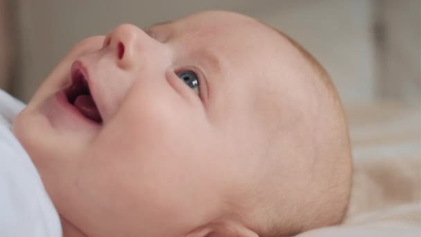 笑着醒来的三个月大的婴儿躺在床单上 感觉很无忧无虑 童年时代快乐 年轻一代的观念 在舒适的床上挂着可爱的新生儿笑脸的特写 — 图库视频影像