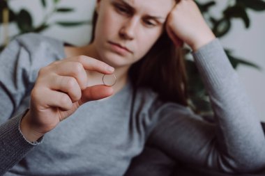 Elinde alyans olan üzgün genç bayanın seçici odak noktası evliliğin bozulması ya da boşanmanın ailevi sorunları olması. İlişkileri bittiği ya da ayrıldığı için mutsuz bir kadın. Aile sorunu