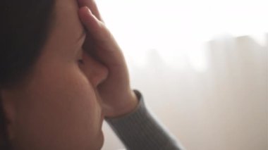 Burun köprüsü şakaklarına masaj yapan mutsuz, genç bir kadın. Evde tek başına kanepede oturuyor. Stresli sağlıksız milenyum kızı migren, panik atak konsepti yüzünden yorgun hissediyor.