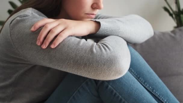 うつ病に悩まされた若い女性は 心の問題を考える不安定な後悔の中絶が自宅のリビングルームのソファーに一人で座っている不安の概念に苦しんでいます — ストック動画