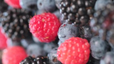 Dönen güzel taze böğürtlenler, çiğ organik çiftçi böğürtlenleri, ahududu, böğürtlen ve yaban mersinlerinin dikey videosu. Şekil meyve çerezi. Vitaminler, doğa, yemek ve yaz konsepti
