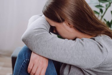 Oturma odasındaki kanepede oturan depresif, üzgün genç bir kadın, zorluklarla yüzleşmek için ifade, başarısızlık ve yorgunluk. Kafkas kadın 25 'li yaşlarda depresyona girmiş yalnız ve evde yalnız hissediyordu.