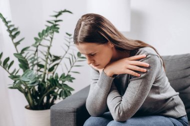 Oturma odasındaki kanepede oturan depresif, üzgün genç bir kadın, zorluklarla yüzleşmek için ifade, başarısızlık ve yorgunluk. Kafkasyalı 25 'li yaşlarda depresyona girmiş yalnız ve evde yalnız hisseden bir kadın.