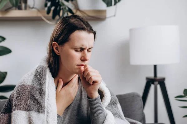 Ill young caucasian lady covered blanket have fever, flu or sore throat and sneezing until chest pain while rest at home. Health care with disease, pandemic virus, coronavirus or covid-19 concept