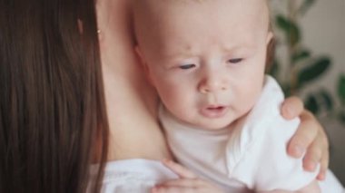 İlgili genç bir annenin ve kollarında doğan tatlı bir çocuğun portresi. Sevgi dolu anne kucağı küçük bebeği kucakla, rahatla evde şefkatli aile anlarının tadını çıkar. Güzel aile, anneler günü konsepti.