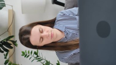 Düşünceli, düşünceli, düşünceli genç beyaz bir kadının ev masasında oturup uzaktan çalışırken, dizüstü bilgisayarda yazarken, internette serbest çalışırken, çalışırken, çalışırken, iş akışı ve iş konsepti yaparken dikey çekimleri.