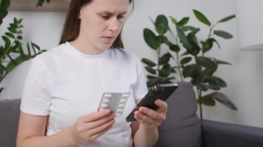 Odaklanmış beyaz bir kadın internetteki reçeteli haplar hakkında internette araştırma yapmak için akıllı telefon kullanıyor. Tıbbi bilgiler hakkında etiket metni, talimatlar yan etkiler, eczane tıbbı