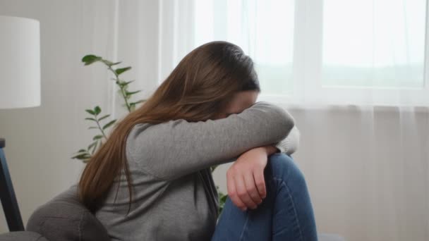 被感情问题困扰的年轻的高加索女人 坐在沙发上 抱着膝盖 双手捂着脸 感到绝望和焦虑 有心理问题 — 图库视频影像