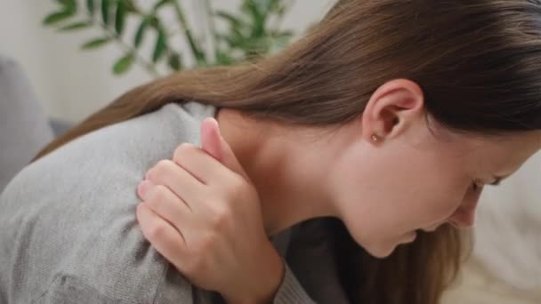 关闭疲惫的年轻女子坐在沙发上在家按摩僵硬而酸痛的脖子紧张的肌肉能减轻疼痛的感觉 肩背痛纤维肌痛骨关节炎老年病的概念 — 图库视频影像