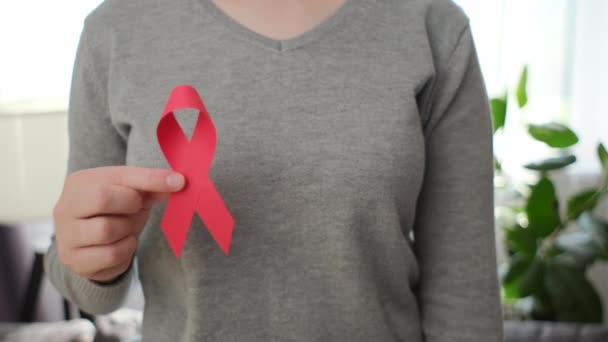 小さな赤いリボン乳がんシンボルを保持している部屋に立っている若い女性が病気の人々をサポートし 女性ボランティアはAidsの病気の意識 医学の概念を保ちます — ストック動画