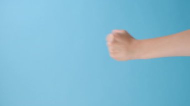 Kızgın, tanınmayan bir kadının el sıkışırken çekilmiş dikey görüntüleri. Mavi stüdyo arka planında kopyalanmış bir şekilde. Reklam alanı, modelle. Tehdit jesti, saldırganlık kavramı, uyarı, ceza