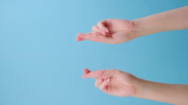 Dua eden kadın ellerinin dikey görüntüleri, mavi arka planda kopyalanmış, iyi bir sonuç için dua ediyor. Vücut dili kavramı. Reklam alanı, çalışma alanı maketi