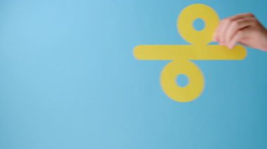 Kadının elinde kağıt sarısı yüzde işareti olan dikey görüntüler, büyük indirimler sunuyor, stüdyoda mavi renkli arka plan duvarının üzerinde izole edilmiş, içerik veya desing için fotokopi alanı var.