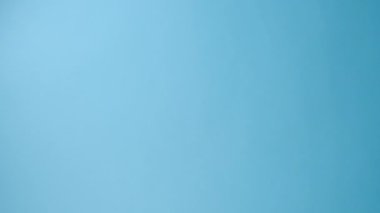 Büyük beyaz kağıt anahtarı tutan kadınların dikey videosu, stüdyodaki pastel mavisi arka plan duvarında poz veriyor ve promosyon içeriği veya tasarımı için fotokopi alanı var. Kira, emlak kavramı