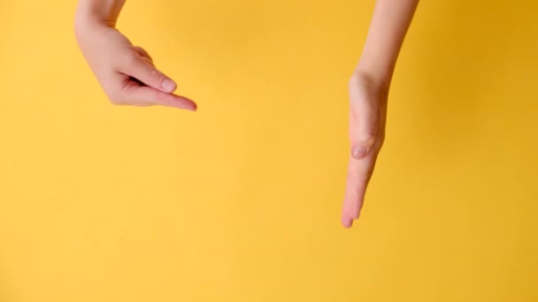 一个不知名的年轻女子敞开的垂直镜头 把手掌放在一边的复制空间上 做成大拇指 与广告隔在黄色的工作室背景墙之上 身体语言概念 — 图库视频影像