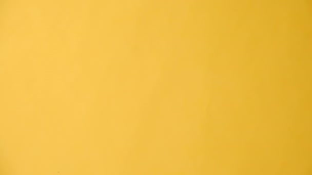 女性の手の垂直ビデオはコピースペースが付いている黄色いスタジオの背景壁の上に隔離された青いリボンを握ります ヘルスケア 国際男性 世界がんデーのコンセプト サポート男性のためのシンボル — ストック動画