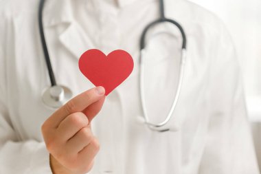 Steteskoplu, beyaz üniformalı, hastanede kırmızı kalp şeklinde küçük bir kadın doktor. Aşk, donör, dünya kalp günü, dünya sağlık günü, CSR bağışı ve sigorta konsepti