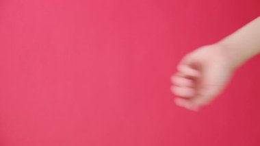 Tanımlanamayan genç beyaz bir kadının kameraya vurduğu dikey bir çekim. Kırmızı stüdyo arka plan duvarında izole edilmiş bir poz. Promosyon içeriği veya tasarımı için fotokopi alanı var. El hareketi konsepti