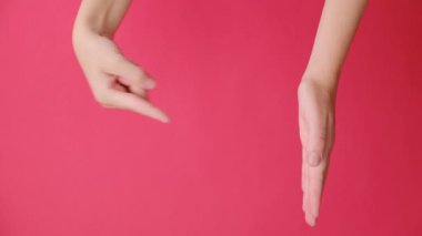 Fotokopi alanındaki avuç içini açıp işaret eden genç bir kadının dikey videosu, kırmızı stüdyo arka plan duvarına reklam ile izole edilmiş bir şekilde baş parmak kaldırıyor. Vücut dili kavramı