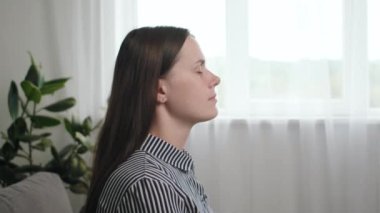 Sakin, genç bir bayan gözlerini kapatıp kanepede dinlenir, derin bir temiz hava alır, evde tek başına dinlenmenin tadını çıkarır, meditasyon pratiği yapar. Stres veya yorgunluk giderici kavram