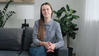Evdeki kanepede oturan genç ve güzel bir kadının portresi. Çekici bir görünüşü ve mutlu bir gülümsemesi var. Kameraya bakıyor, mutluluk yayıyor. Memnun kiracı ya da ev sahibi