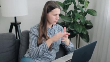 Ciddi, genç, beyaz bir kadın evdeki kanepede oturur, bilgisayarını kapatır, yapılmamış projeyi düşünür, iş yerinde oturur, görevinin zamanında bitmediğini hisseder.