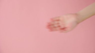 Kadın el sallamasının dikey görüntüleri, veda jesti, stüdyodaki pastel pembe arka plan duvarında izole edilmiş poz, içerik ve tasarım için fotokopi alanı. Vücut dili kavramı